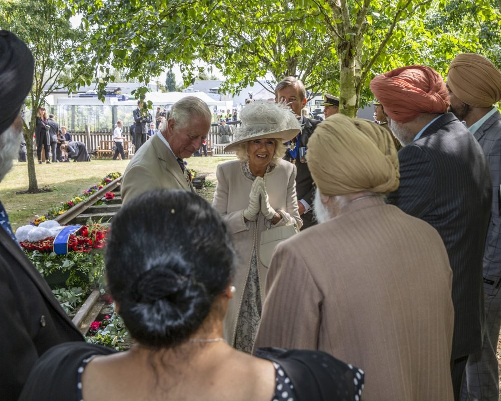 The Prince of Wales and The Duchess of Cornwall meet Darbara Singh Bhullar, a Sikh veteran with a namaste greeting, at the National Memorial Arboretum in Staffordshire today, to mark VJ Day. (MoD)