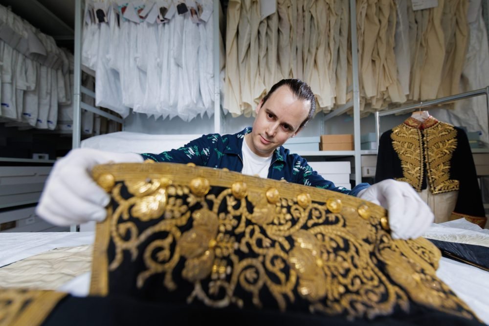 Curator Matthew Storey examining an early 20th-century Japanese Court Suit coatee in the Royal Ceremonial Dress Collection store