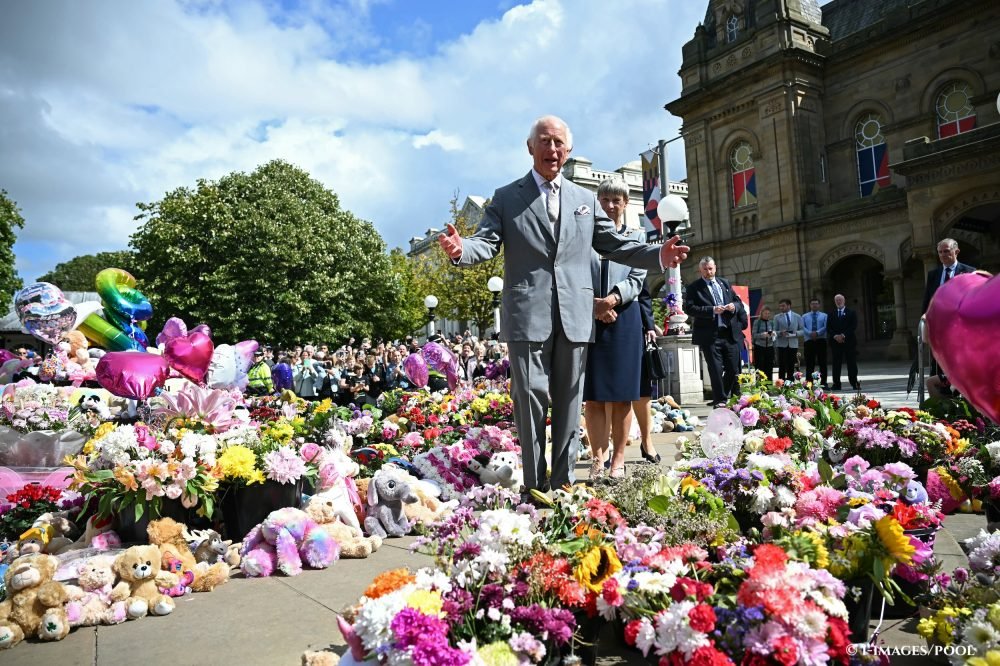 King Charles III looks at floral tributes during a visit to Southport, following the killing of three children and the riot in the town